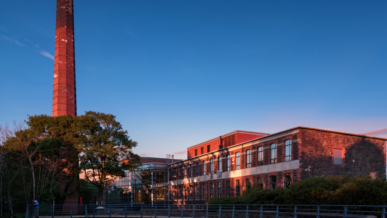 The restored Victorian Mossley Mill with its landmark brick chimney and footbridge over the millpond