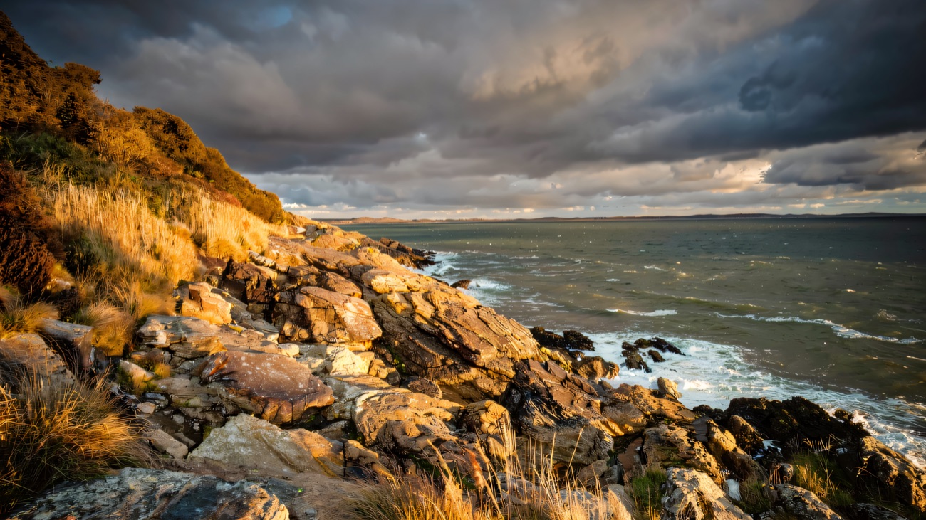 Waves break over the rugged rocks along the Mourne shoreline