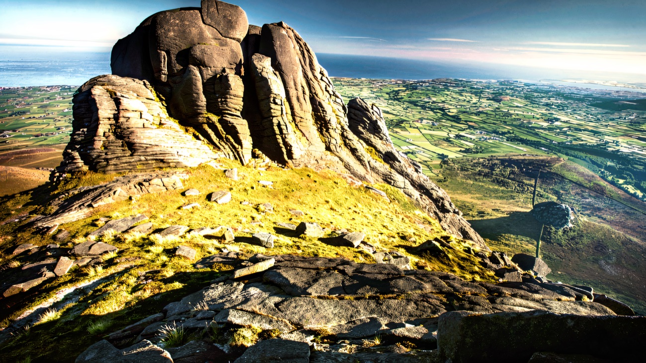 A dramatic granite tor high on the ridge above the patchwork fields and sea