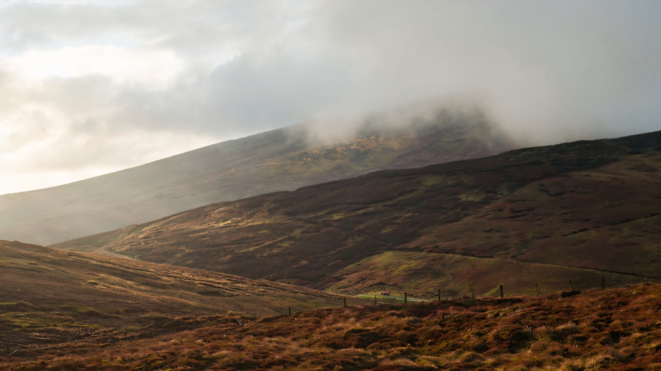 Cloud spilling over a heather-brown Sperrins summit, the moorland glowing in low light.