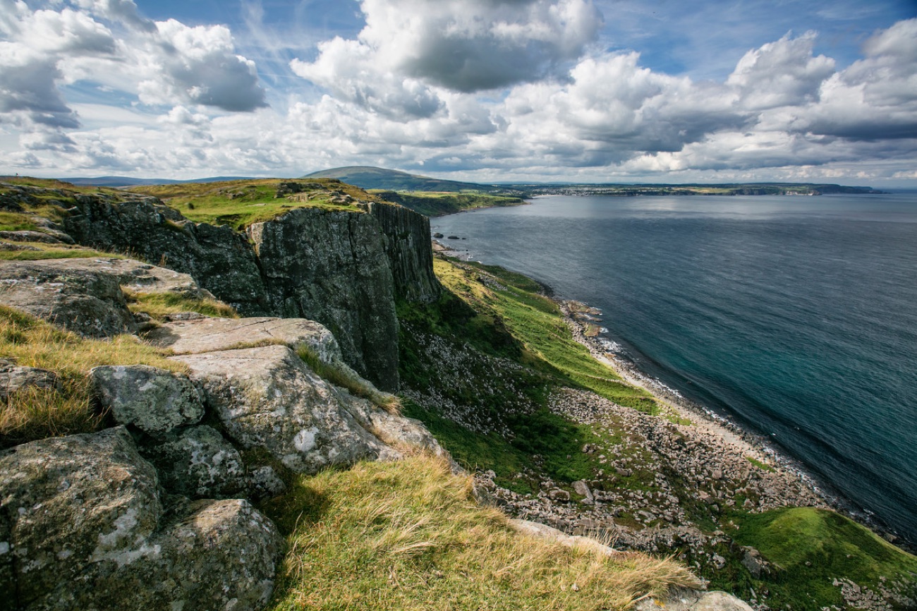 Rugged cliffs and a rocky shoreline dropping to the blue sea on the Fair Head coast
