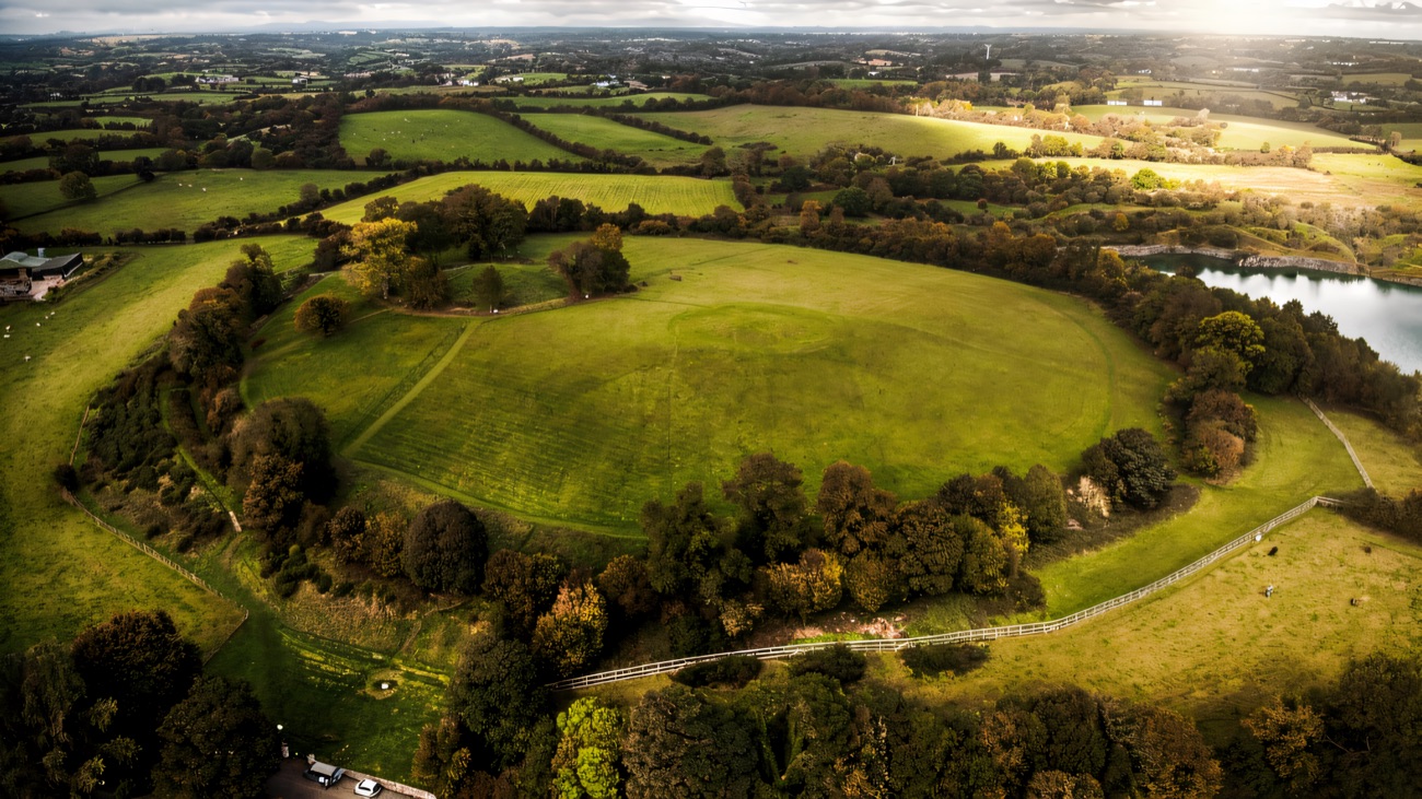 Autumn aerial of the whole Navan Fort enclosure with a quarry lake in the distance