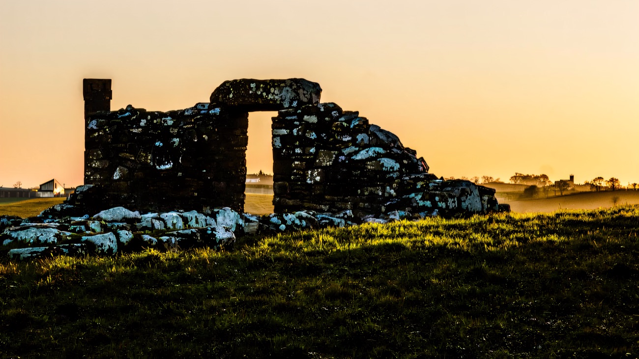 The ruins in silhouette against a glowing evening sky.