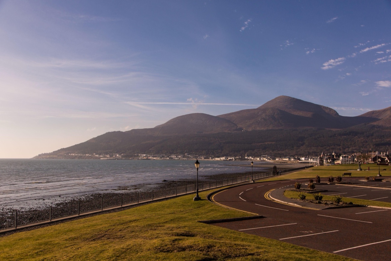 The Newcastle seafront promenade curving along the shore with old-style lamp posts and Slieve Donard behind