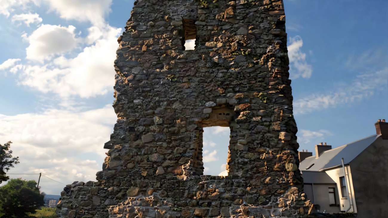 The tall tower-house ruin with its window openings against a summer sky.