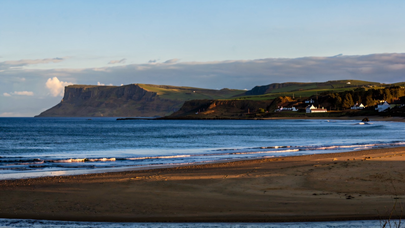 The wide sandy sweep of Ballycastle beach with the flat-topped headland of Fair Head rising across the bay