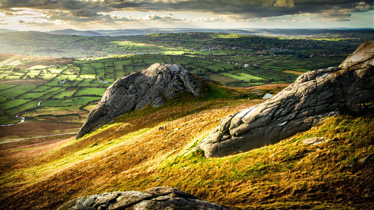 Granite tors on the open hillside, looking out over patchwork fields and the country below