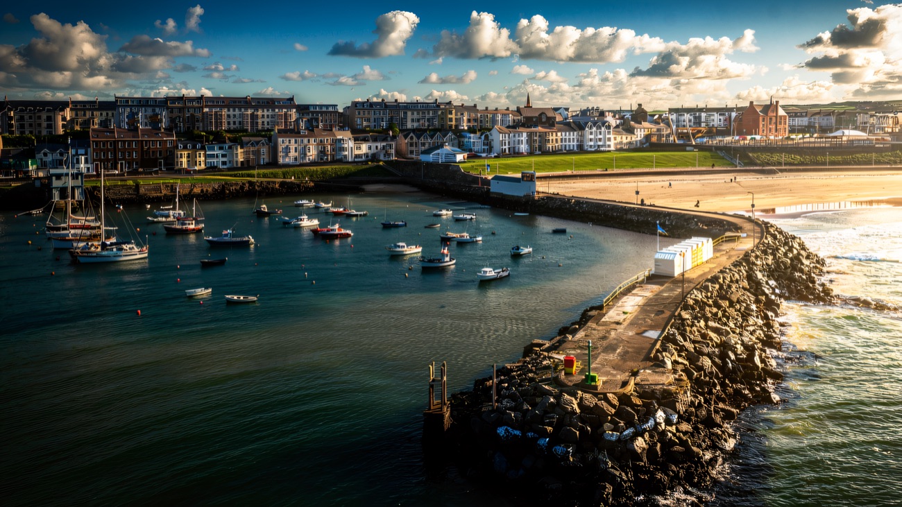 Portrush harbour and its pier from the air, boats swinging on their moorings