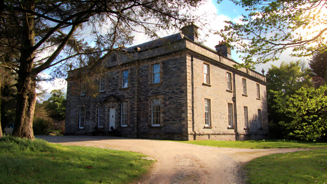 Prehen House framed by mature trees along its wooded drive above the River Foyle