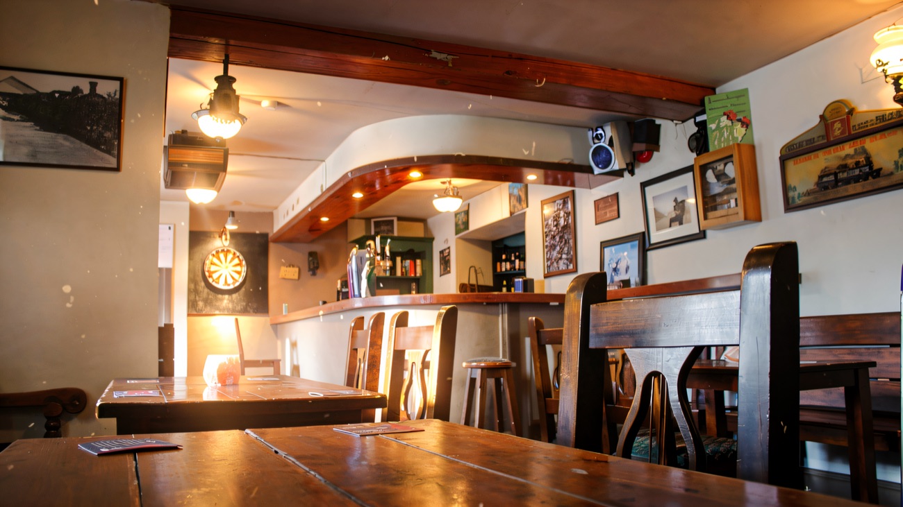 The quiet bar room with wooden tables and benches, a dartboard and old railway pictures on the walls