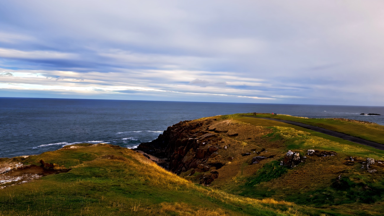 The grassy headland and its rocky outcrop, open sea beyond