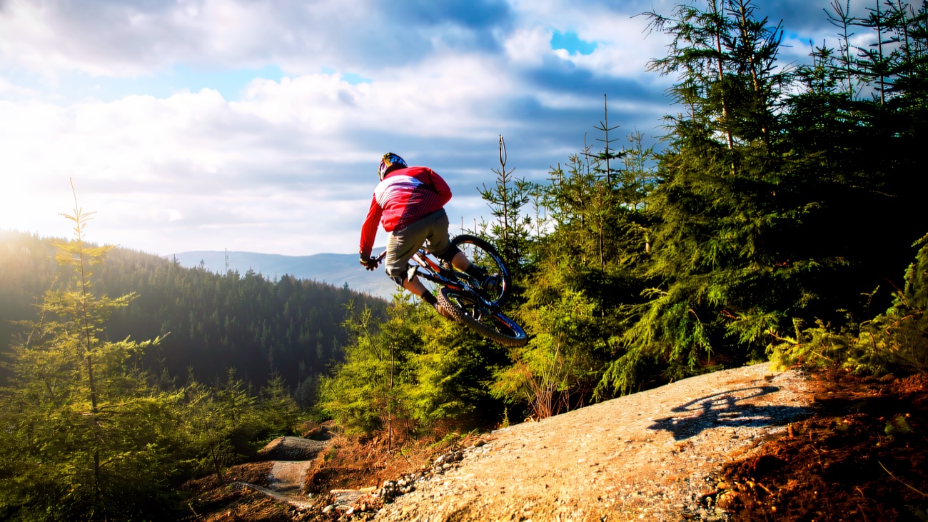 Launching off a rock slab with the forested hills rolling away behind
