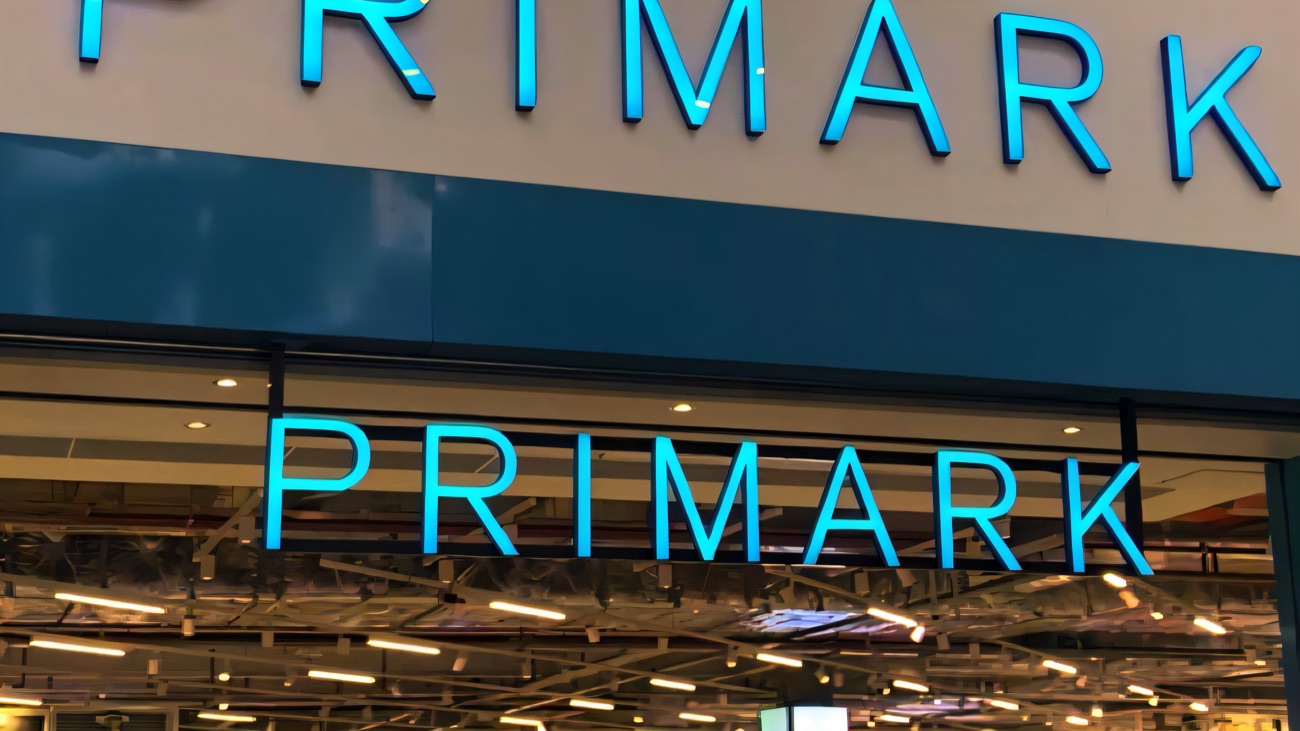 The blue-lit Primark storefront inside the mall at Rushmere Shopping Centre, with the shop floor glowing beyond the entrance