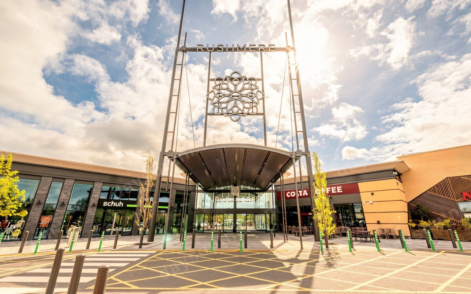 The rebuilt main entrance of Rushmere Shopping Centre in Craigavon under a bright sky, with the tall Rushmere sign tower and paved plaza in front