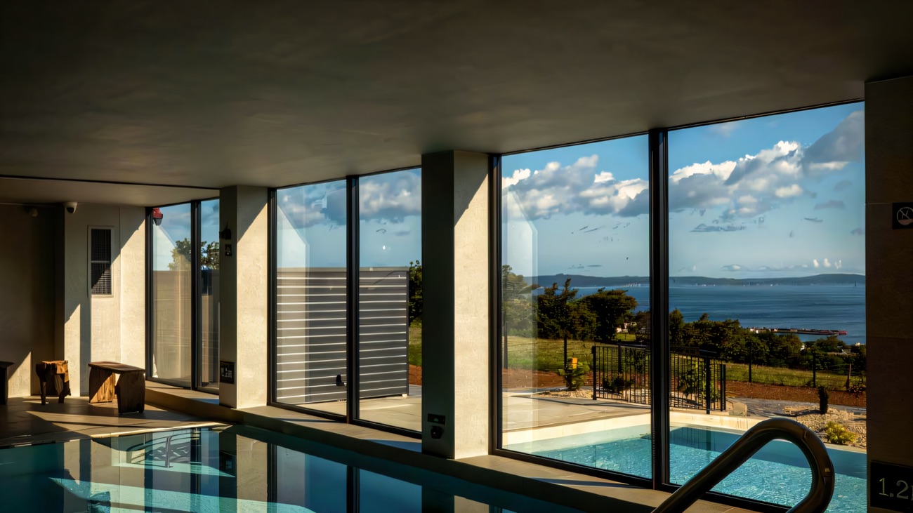 The indoor vitality pool with floor-to-ceiling windows opening onto the coast.