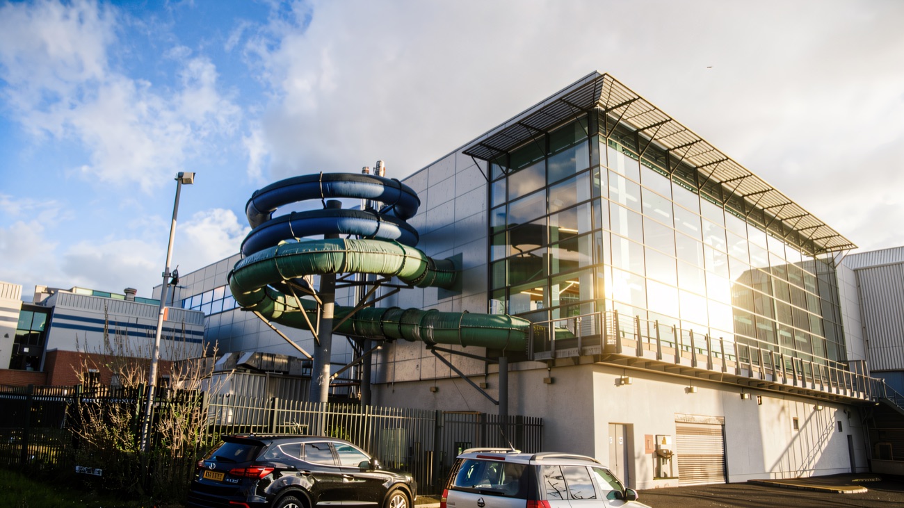 The centre's blue and green water flumes coiling outside the glass-fronted building