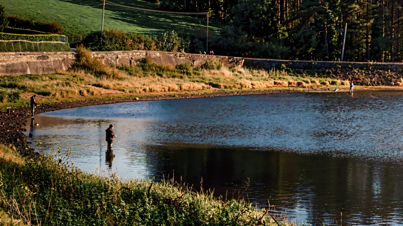 The lake below its stone dam wall on a bright autumn day