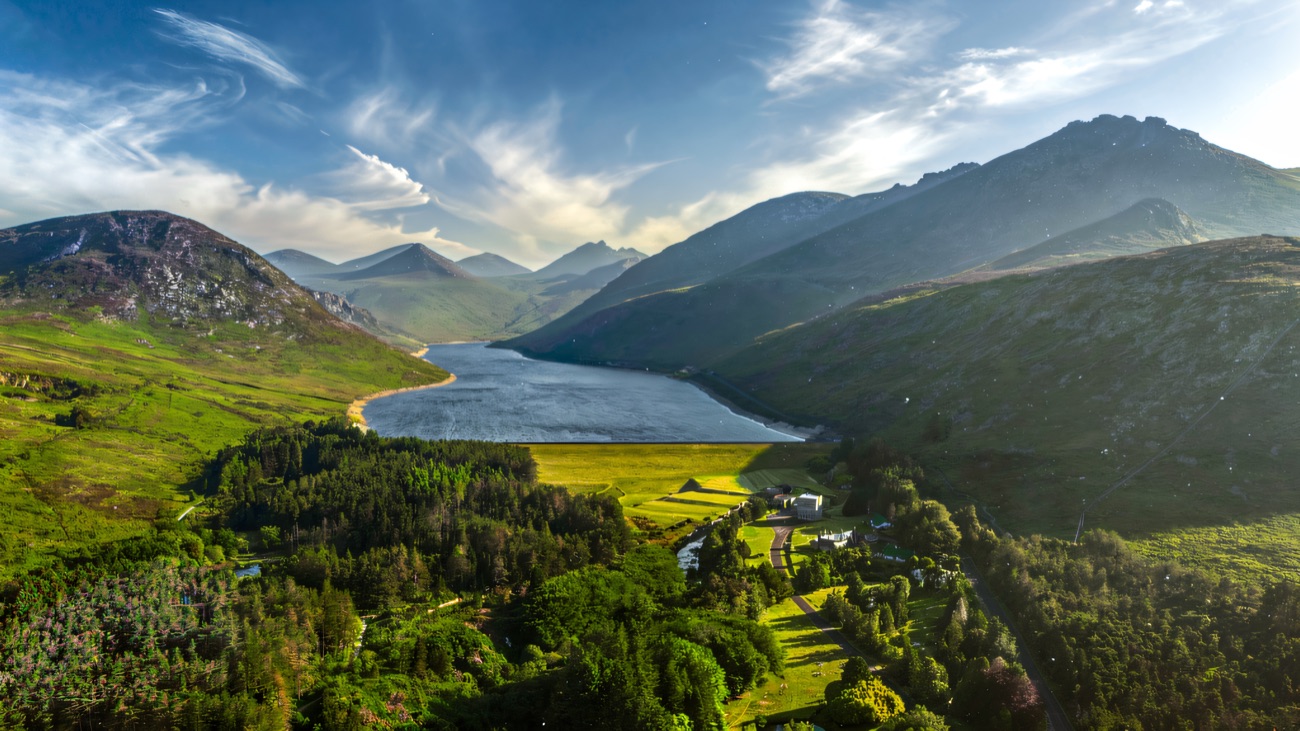 Aerial view over the wooded valley park and visitor centre with the reservoir and Mourne Mountains behind