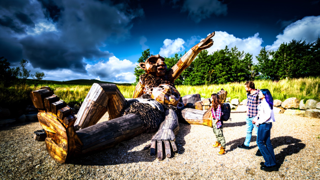 Visitors give a sense of the giant's scale as they meet the storyteller on his gravel clearing.