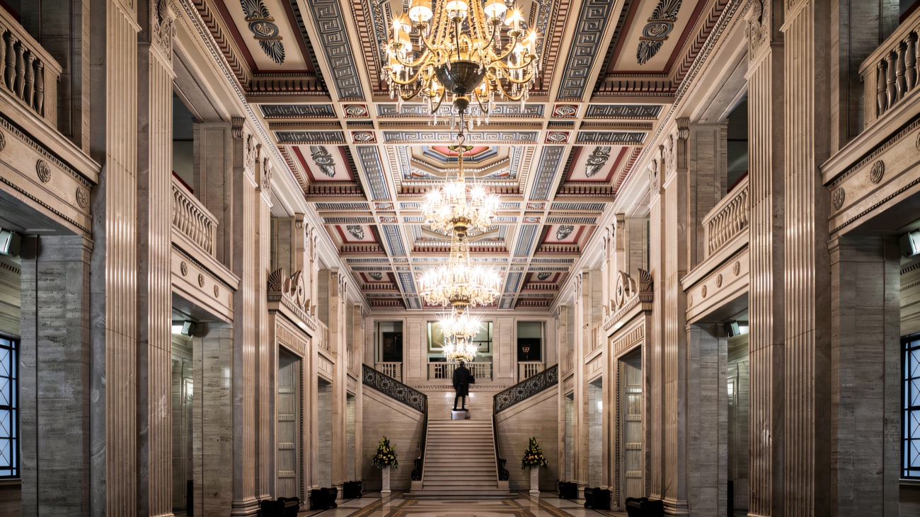 The Great Hall inside Parliament Buildings — marble columns, a painted coffered ceiling and the grand staircase