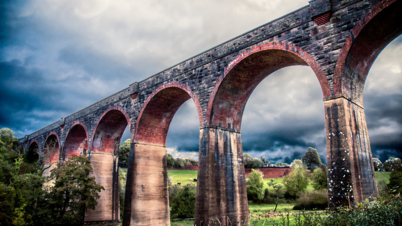 A low view of the brick arches under a brooding, stormy sky.