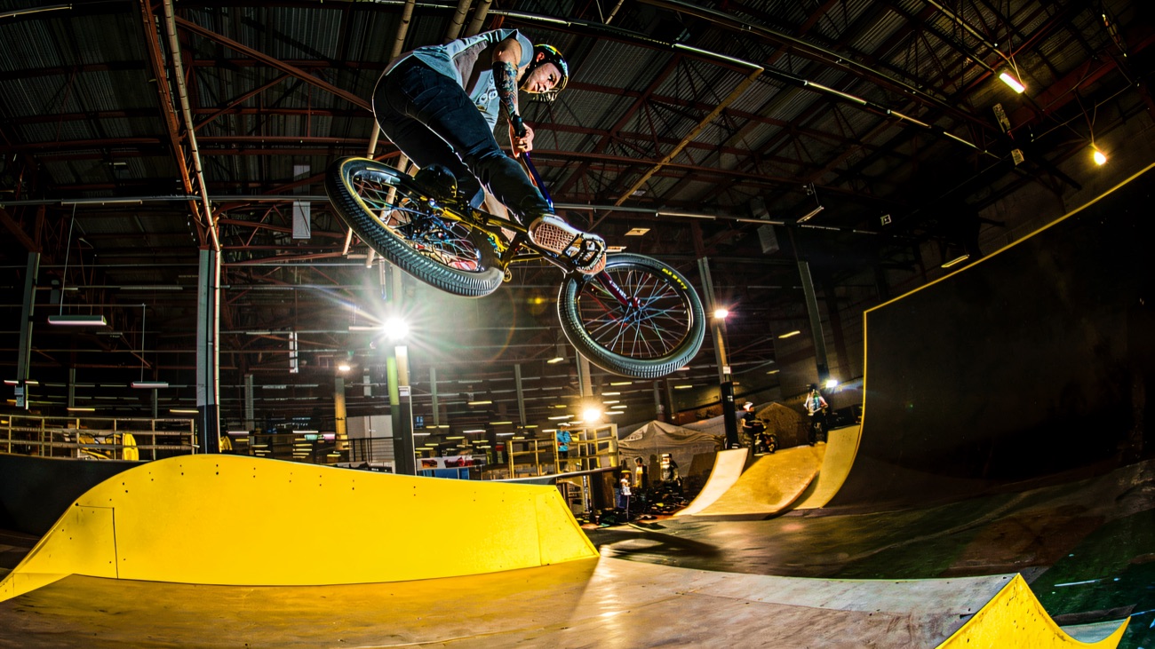 BMX rider launching off a yellow ramp inside the indoor park