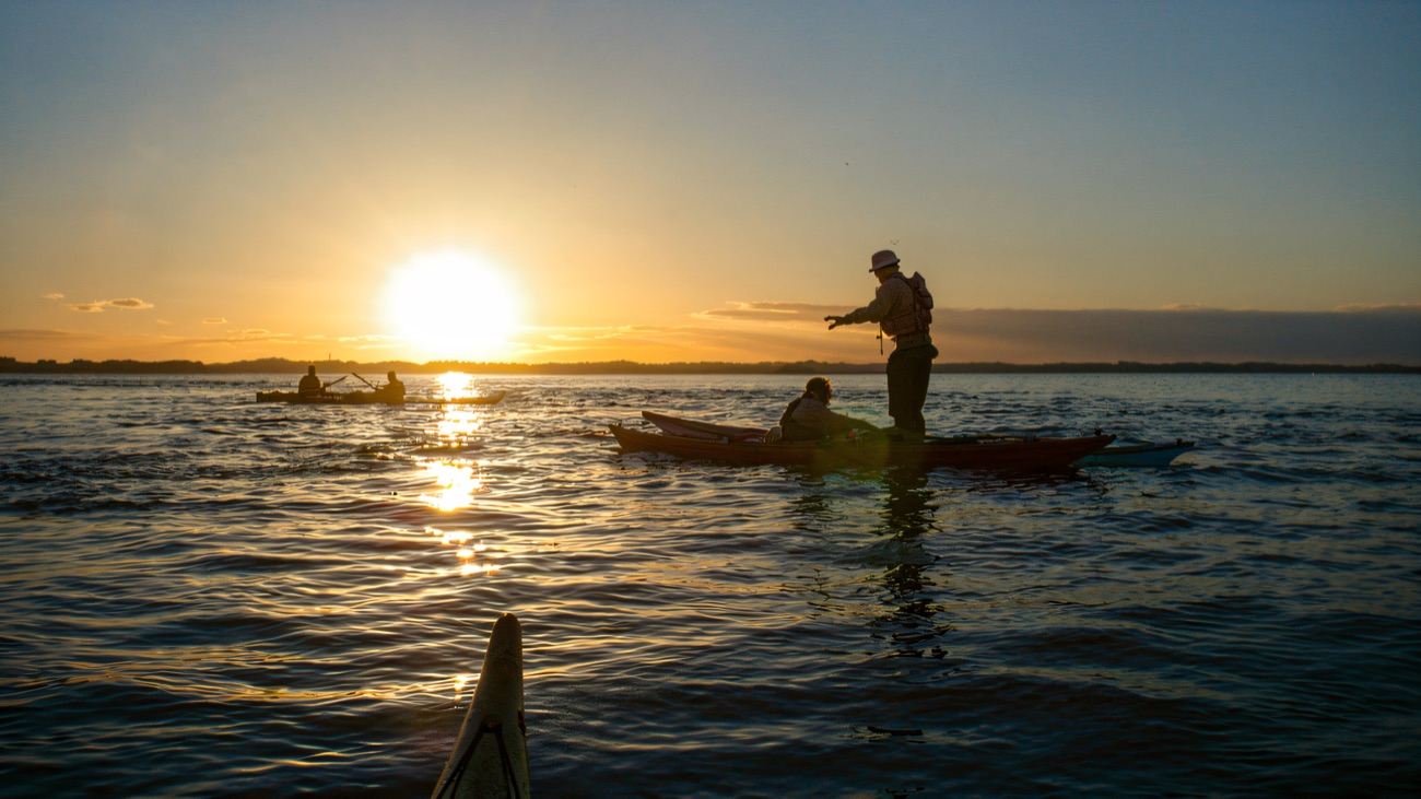 Sea kayaks slipping across the lough as the sun drops to the horizon