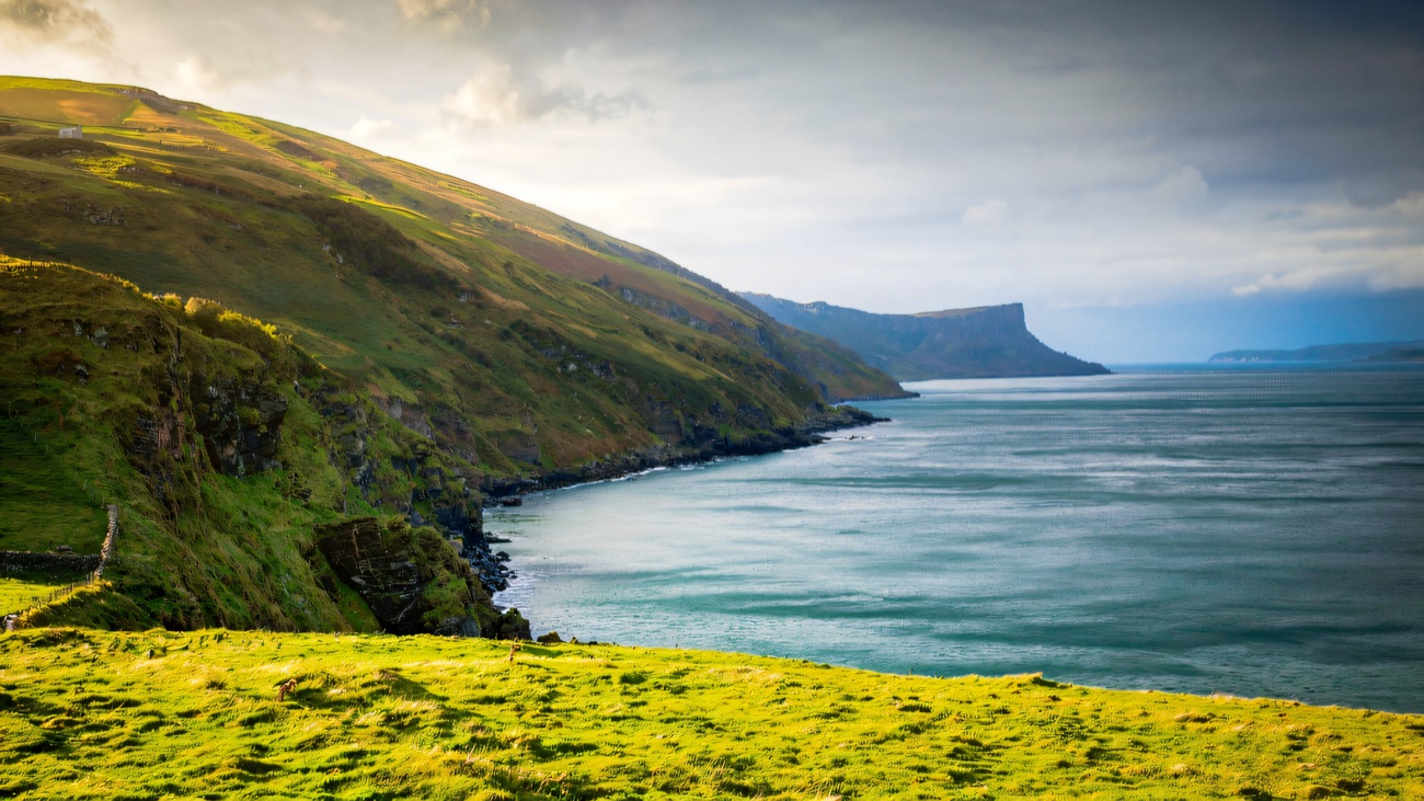 Vivid green cliffs curving away toward Fair Head in the distance