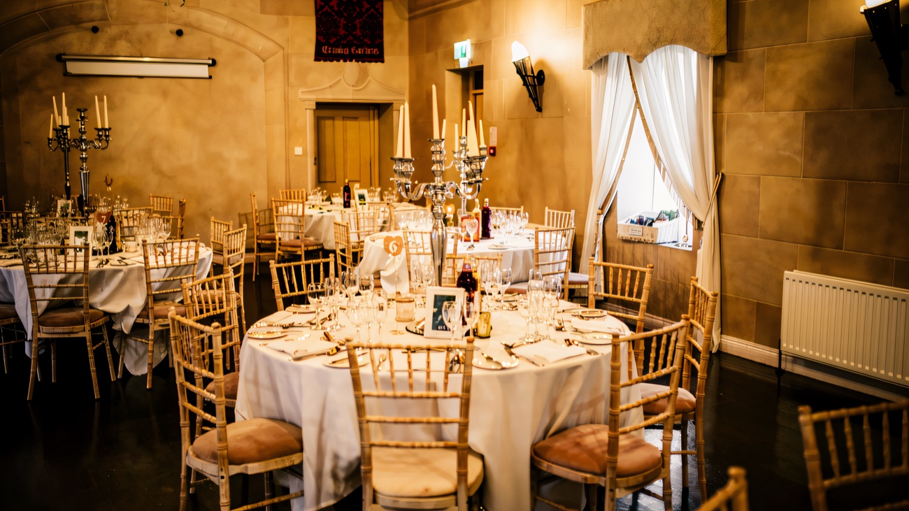 A stone-walled dining room at Tullylagan laid with round tables, white linen and candelabra for an event