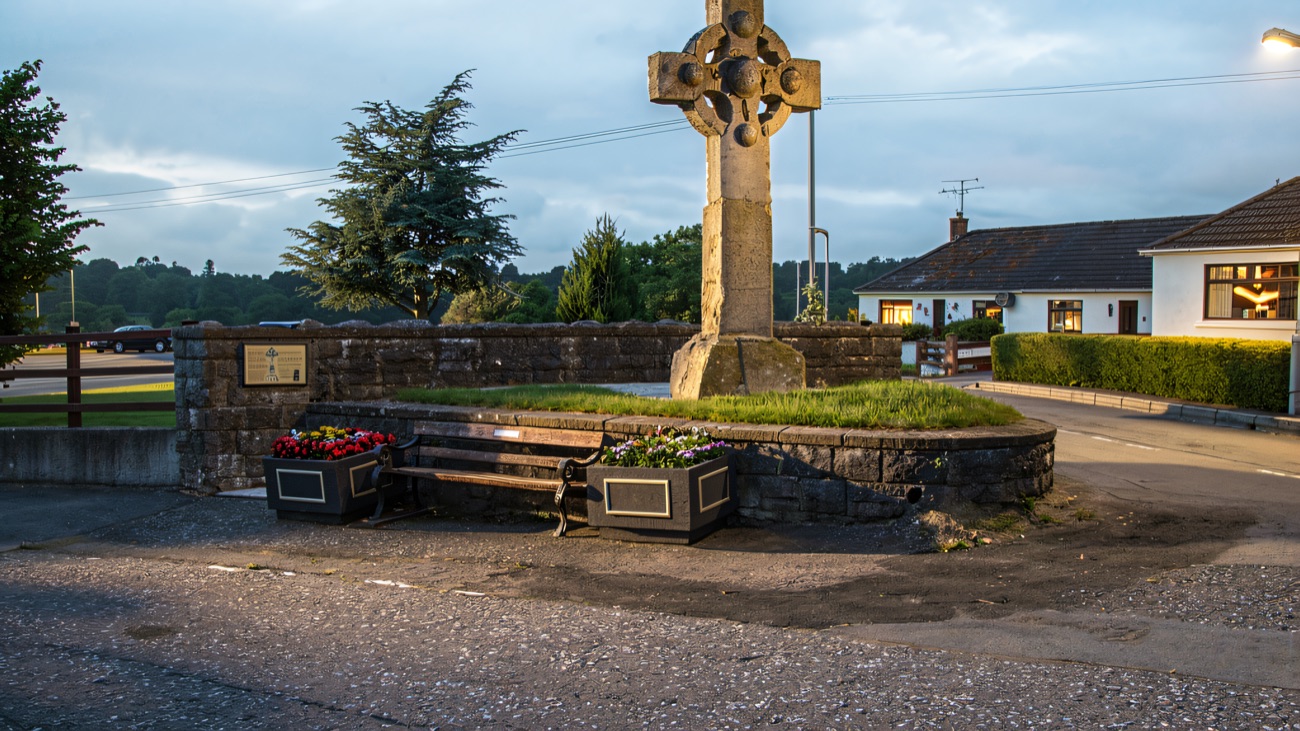 The carved stone high cross on its grassy island in the middle of the village