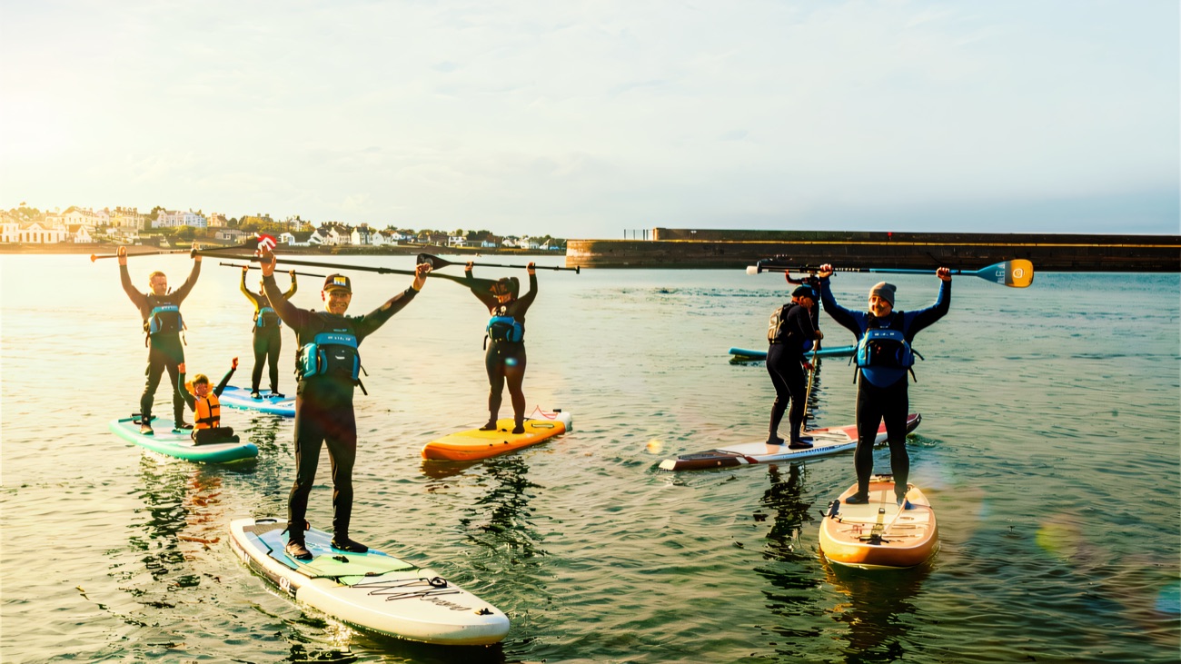Paddles up and cheering by the old harbour wall