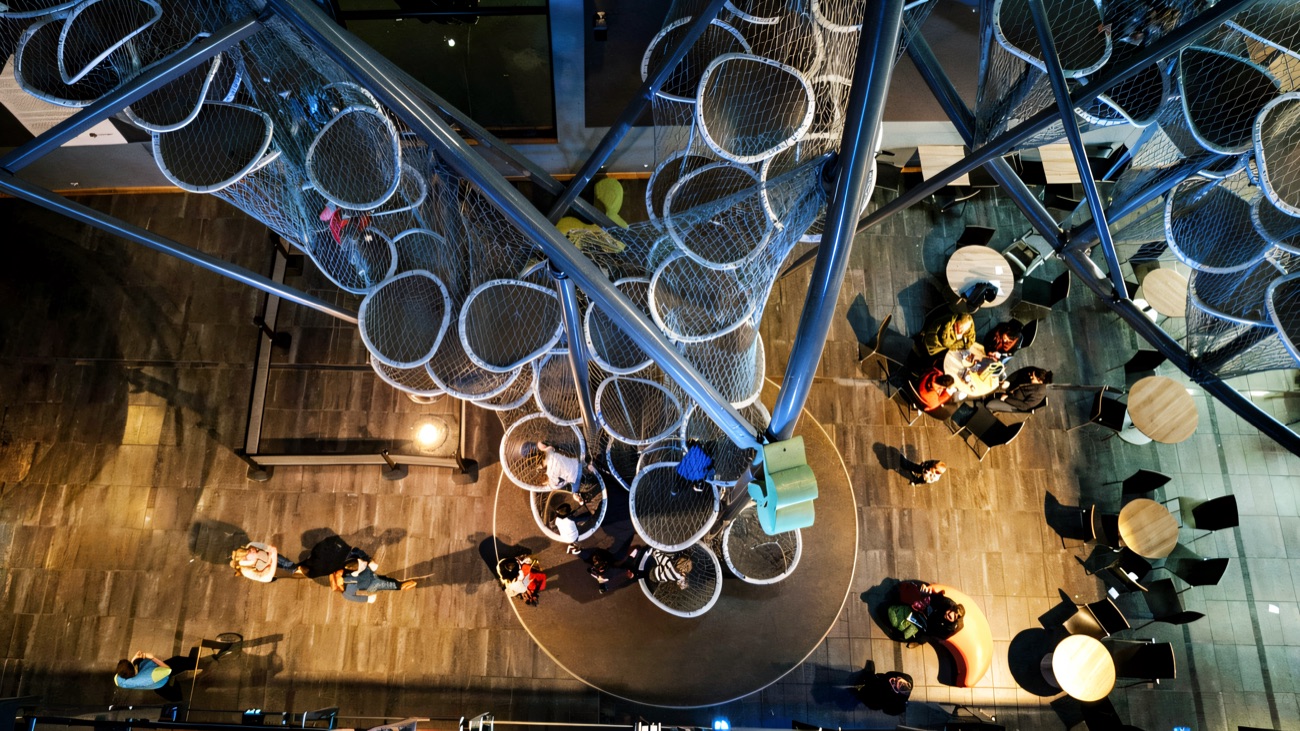 The Climbit climbing sculpture rising through the atrium of W5, seen from above with café tables below