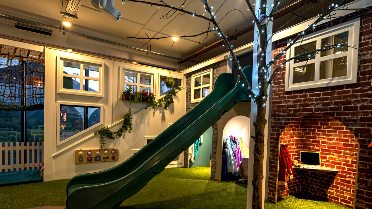 The role-play village with a green slide, dress-up rail and a sparkling indoor tree