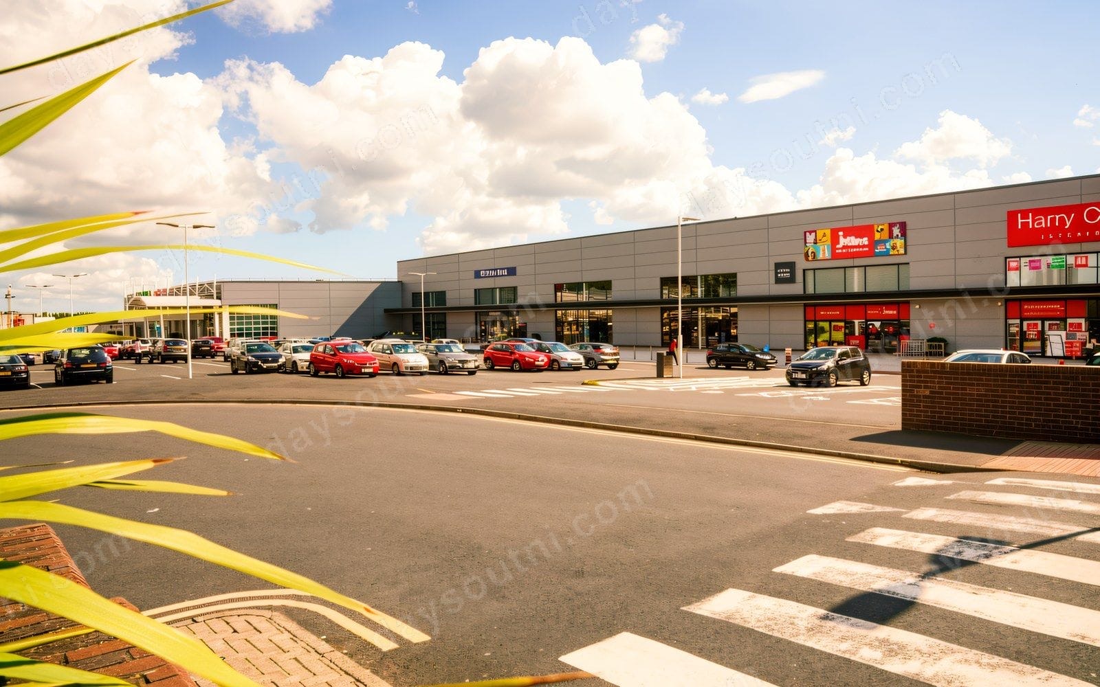 The Westwood Centre from the car park, with the Harry Corry and Jollees units along the retail-park frontage and shoppers' cars parked outside