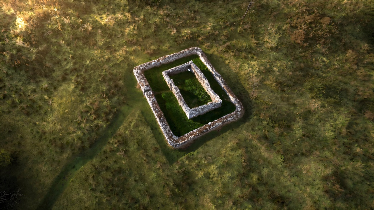 An aerial view of the small church ruin within its rectangular enclosure on the island.