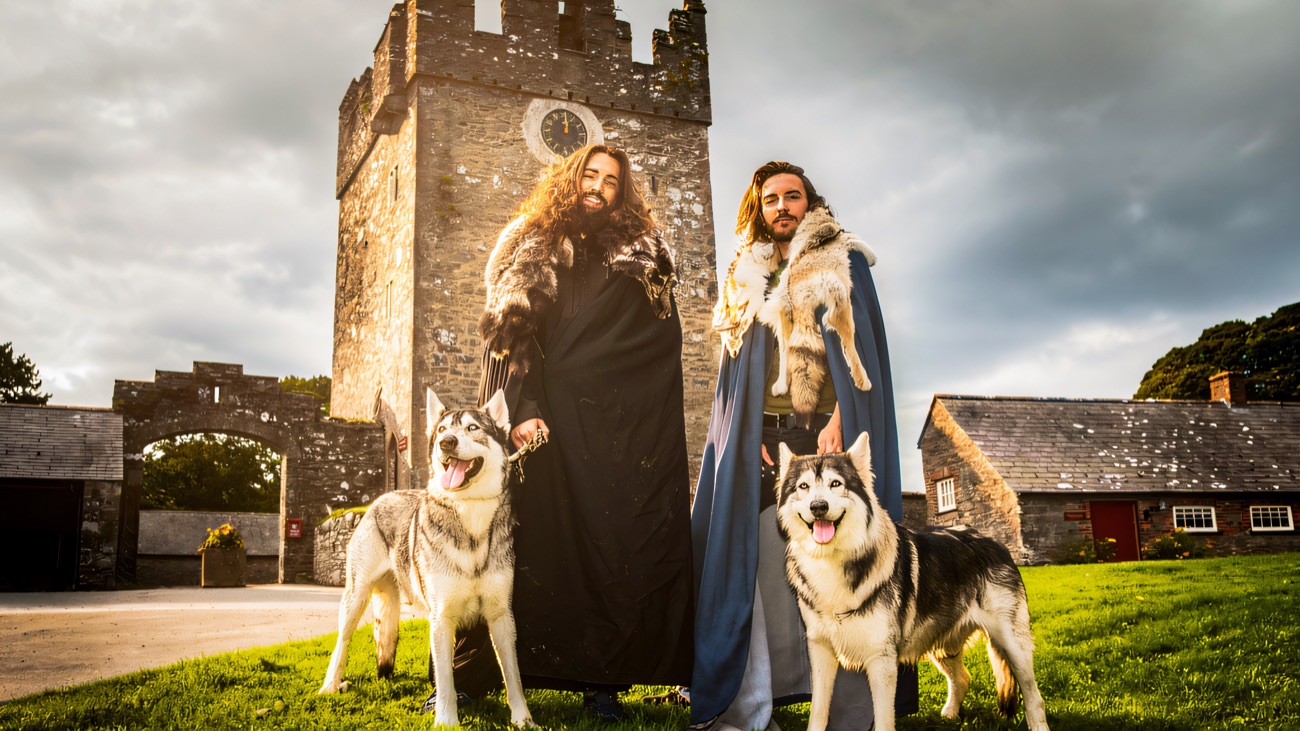 Cloaked guides and their two direwolves at the foot of the tower